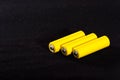 Three yellow batteries close-up on a dark black blurred background. Electrics. Battery power. Accumulator on the fabric with vill Royalty Free Stock Photo