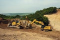 Three yellow chain excavators digging on a slope