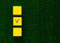 Three yellow cubes with a tick on one on grass