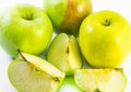 Three yellow and green apples and three slices on a white background