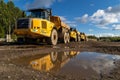 Three yellow industrial construction machinery situated on a dirt surface