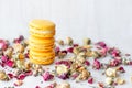 Three yellow macarons cookies and dry rose flowers on light background Royalty Free Stock Photo