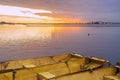 Three yellow metal boats tied together on calm lake at dawn under a brilliant gold and violet sunrise Royalty Free Stock Photo