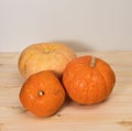 Three yellow-orange pumpkins on a light wooden table, Halloween concept and autumn pumpkin harvest, farm product Royalty Free Stock Photo