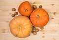 Three yellow-orange pumpkins and scattered walnuts on a wooden table, Halloween concept and autumn harvest of pumpkins, farm Royalty Free Stock Photo