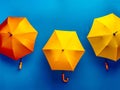Three yellow and orange umbrellas hanging on a blue wall Royalty Free Stock Photo