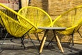 Three yellow plastic chairs  and a table on plank patio Royalty Free Stock Photo