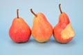 Three yellow-red pears are lined up side by side. One pear has been bitten off a large piece