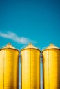 Three yellow silos are standing in row on sunny day. Generative AI Royalty Free Stock Photo