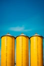 Three yellow silos are standing in row on sunny day. Generative AI Royalty Free Stock Photo