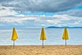 Three yellow sunshades on sandy beach against blue sky, Sithonia Royalty Free Stock Photo