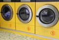 Three yellow washing machines in laundromats Royalty Free Stock Photo