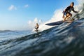 Three young adult surfers rides the wave of the ocean at the surf spot