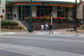 Three young African American crossing the street with a group of silver and black electric scooters on the corner