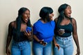 Three young african american friends using smartphone angry and mad screaming frustrated and furious, shouting with anger