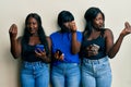 Three young african american friends using smartphone doing italian gesture with hand and fingers confident expression Royalty Free Stock Photo