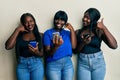 Three young african american friends using smartphone smiling doing phone gesture with hand and fingers like talking on the Royalty Free Stock Photo