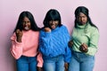 Three young african american friends wearing wool winter sweater angry and mad raising fist frustrated and furious while shouting