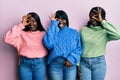 Three young african american friends wearing wool winter sweater doing ok gesture with hand smiling, eye looking through fingers Royalty Free Stock Photo