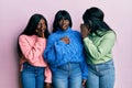 Three young african american friends wearing wool winter sweater hand on mouth telling secret rumor, whispering malicious talk Royalty Free Stock Photo