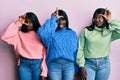 Three young african american friends wearing wool winter sweater making fun of people with fingers on forehead doing loser gesture Royalty Free Stock Photo