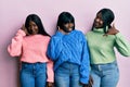 Three young african american friends wearing wool winter sweater smiling doing phone gesture with hand and fingers like talking on Royalty Free Stock Photo