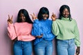 Three young african american friends wearing wool winter sweater smiling with happy face winking at the camera doing victory sign Royalty Free Stock Photo