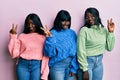Three young african american friends wearing wool winter sweater smiling looking to the camera showing fingers doing victory sign Royalty Free Stock Photo