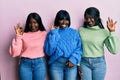 Three young african american friends wearing wool winter sweater smiling positive doing ok sign with hand and fingers Royalty Free Stock Photo