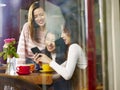 Three young asian women looking at mobile phone in coffee shop Royalty Free Stock Photo