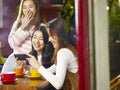 Three young asian women looking at mobile phone and laughing in Royalty Free Stock Photo