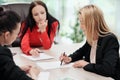 Three young attractive women in business suits are sitting at a desk and discussing workflows. Head and subordinates Royalty Free Stock Photo