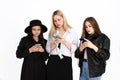 Three young beautiful girls are looking at their smartphones