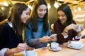 Three young beautiful women using mobile phone at cafe shop. Royalty Free Stock Photo