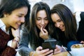 Three young beautiful women using mobile phone at cafe shop. Royalty Free Stock Photo