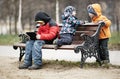 Three young boys playing on a park bench in winter Royalty Free Stock Photo