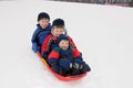 Three young boys sledding downhill together Royalty Free Stock Photo