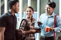 Three young and cheerful employees at their workplace talking in the morning