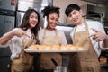 Three young chefs with baking bread, smile and are cheerful in the kitchen