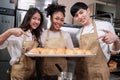 Three young chefs with baking bread, smile and are cheerful in the kitchen