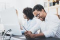 Three young coworkers working together in a modern office.African american man in white shirt smiling in workplace.