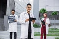 Three young doctors, working with tablet pc, xray and patient's medical record outside the hospital Royalty Free Stock Photo