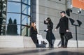 A trio of young entrepreneurs having an outdoor business discussion in a city setting, conveying modern, collaborative