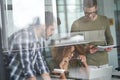 Three young focused colleagues or coworkers looking at laptop and discussing new project while working together in the Royalty Free Stock Photo