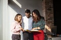 Three young focused coworkers, women and man, looking through documents from folder standing in office Royalty Free Stock Photo