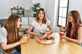 Three young friends woman smiling happy having breakfast sitting on the table at home