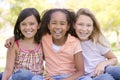 Three young girl friends sitting outdoors