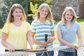 Three young girl friends on tennis court smiling