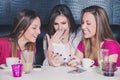 Three young girls laughing while looking at the mobile phone in Royalty Free Stock Photo