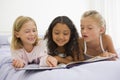 Three Young Girls Lying On A Bed In Their Pajamas